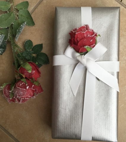 Silver wrapped gift with white ribbon and rose embellishment