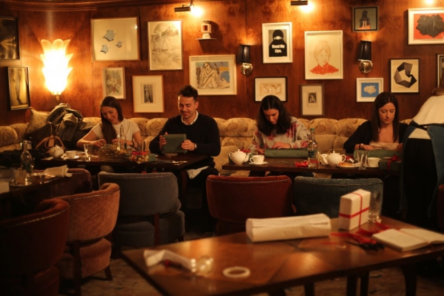 Several people trying out giftwrapping techniques in the vault at The Ned, London