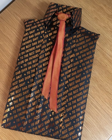 A book wrapped to look like a shirt using black giftwrap & a copper tie