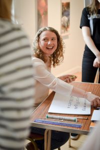 Angela Reed sat at a desk with her calligraphy materials on a table in front of her