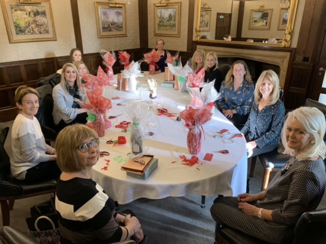 A group of ladies sat at a table with their giftwrapped creations including boxes and bottles