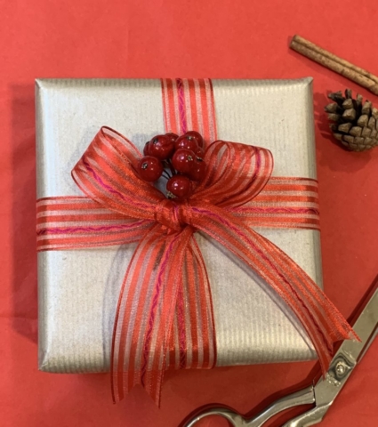 A box wrapped in silver paper with a red ribbon and bow